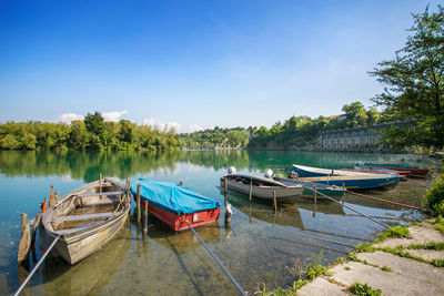 Boats moored in lake against clear blue sky