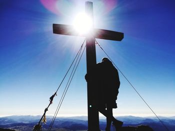 Low angle view of silhouette man standing on rope against sky