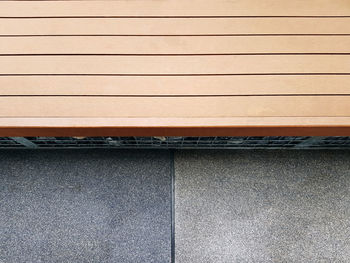 High angle view of wooden plank bench by the street