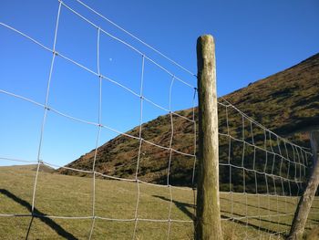 Fence on landscape against clear sky