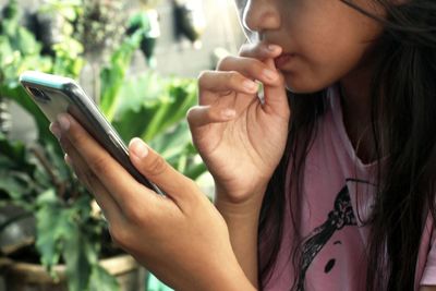 Midsection of girl looking at smart phone at home