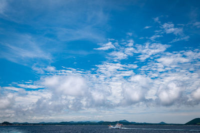 Boat sailing under cloudy blue sky