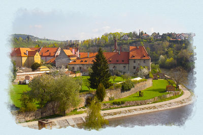 High angle view of houses by river and buildings against sky