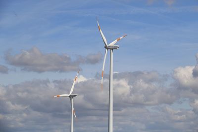 Low angle view of windmill against cloudy sky on sunny day