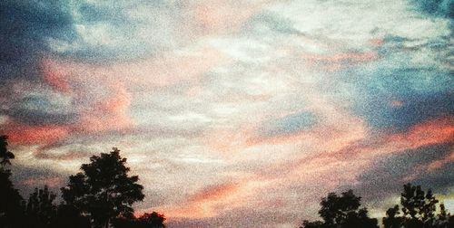 Low angle view of silhouette trees against cloudy sky