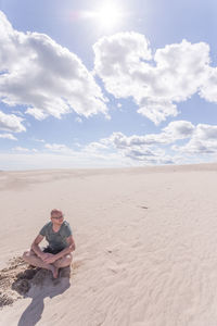 Man surfing on sand at beach against sky