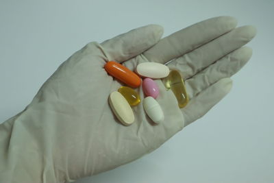 Close-up of hand holding colored pencils over white background