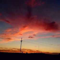 Low angle view of electricity pylon against dramatic sky