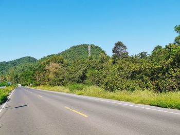 Road by trees against clear sky