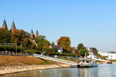 Scenic view of river by buildings against clear sky