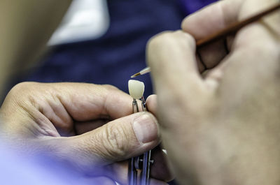Cropped hands of person cleaning dentures in clinic