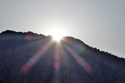 Sunlight streaming on mountain against sky during sunset