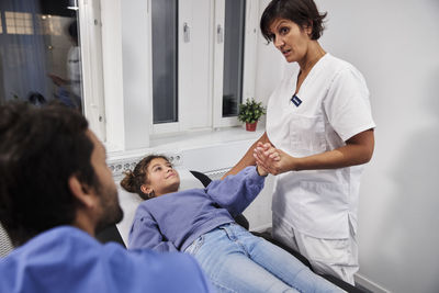 Doctors examining girl patient's arm during appointment