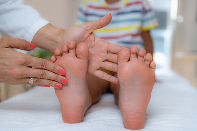 Pediatrician examining development boys feet on a bed.