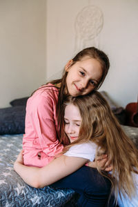 Portrait of young woman sitting on bed at home