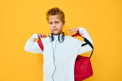 Portrait of young woman holding stethoscope against yellow background