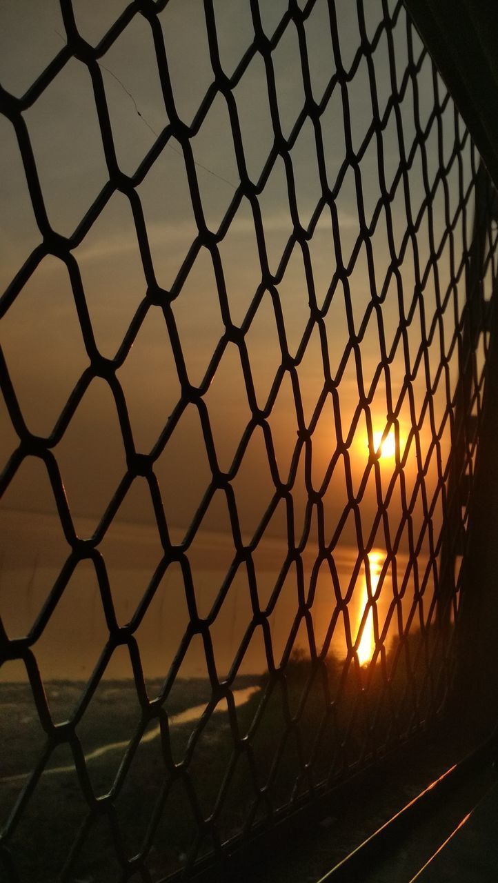 FULL FRAME SHOT OF CHAINLINK FENCE AT SUNSET