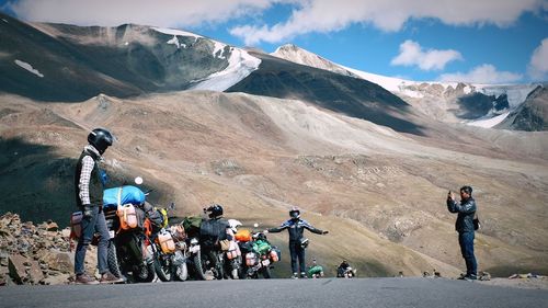 People riding motorcycle on road against mountain range