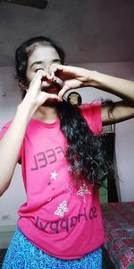 Midsection of woman holding pink while standing at home