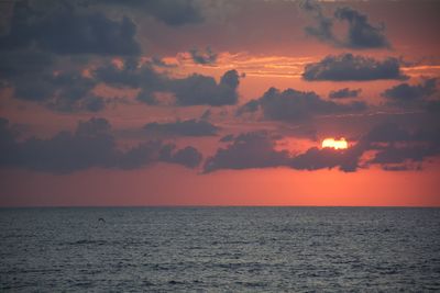 Scenic view of sea against dramatic sky during sunset