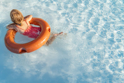 High angle view of girl floating in swimming pool