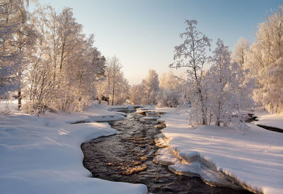 The river flows through the snowy rural landscape. the water has not been totally frozen.