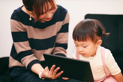 Mother with daughter using digital tablet at home