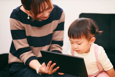 Mother and daughter using mobile phone at home