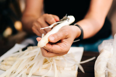 Midsection of woman peeling vegetable