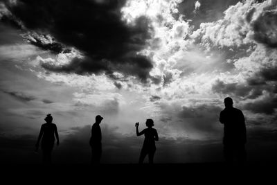 Silhouette people standing on land against sky during sunset