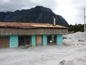 House by mountain against sky