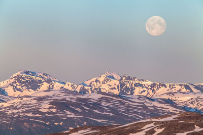 Tranquil view of snowcapped mountains against moon in sky