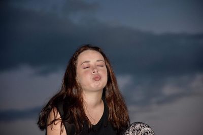 Woman puckering lips against sky at night