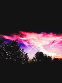 Low angle view of silhouette trees against dramatic sky