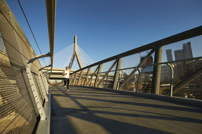 Man on footbridge against clear sky