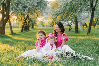 Cute mom and two daughters are having a picnic in the spring garden. outdoor activity.