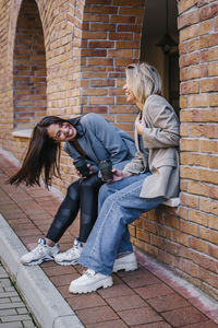 Happy friends enjoying coffee sitting on wall