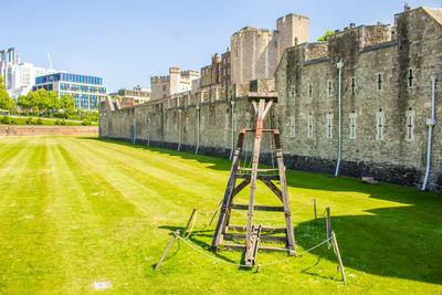 Lawn by building against sky on sunny day