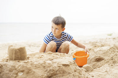 Side view of boy sitting at beach