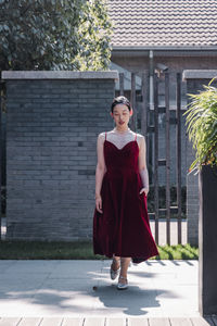 Portrait of young woman walking against built structure