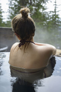 Rear view of woman relaxing in hot spring
