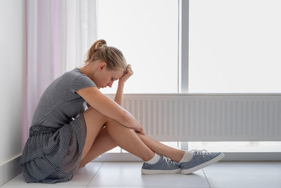 Mental health. depressed young woman in gray shirt and skirt sitting on the floor