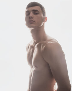 Low angle view of shirtless man standing against white background