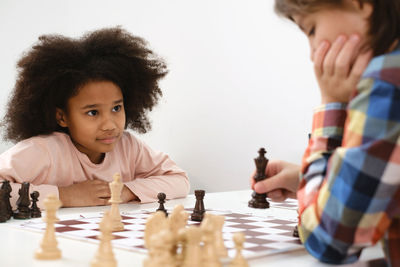 Diverse group of kids playing chess. concentrated multiethnic clever children with board game having