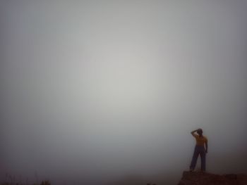 Side view of woman standing on land against sky