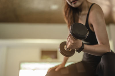 Low angle view of woman lifting dumbbell in gym