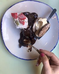 Close-up of hand holding ice cream cone in plate