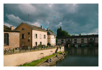 Houses by river against sky