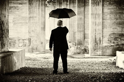 Rear view of man with umbrella walking in rain