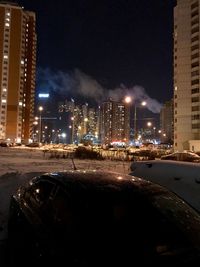 Illuminated buildings in city against sky at night